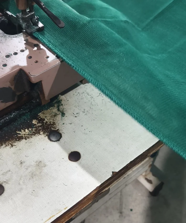 Green net edge being sewn at a sewing machine